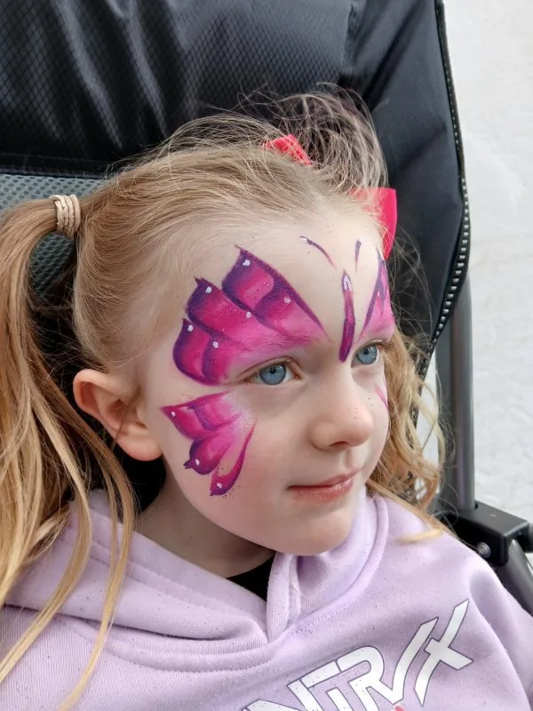 Child with pink and purple butterfly face paint